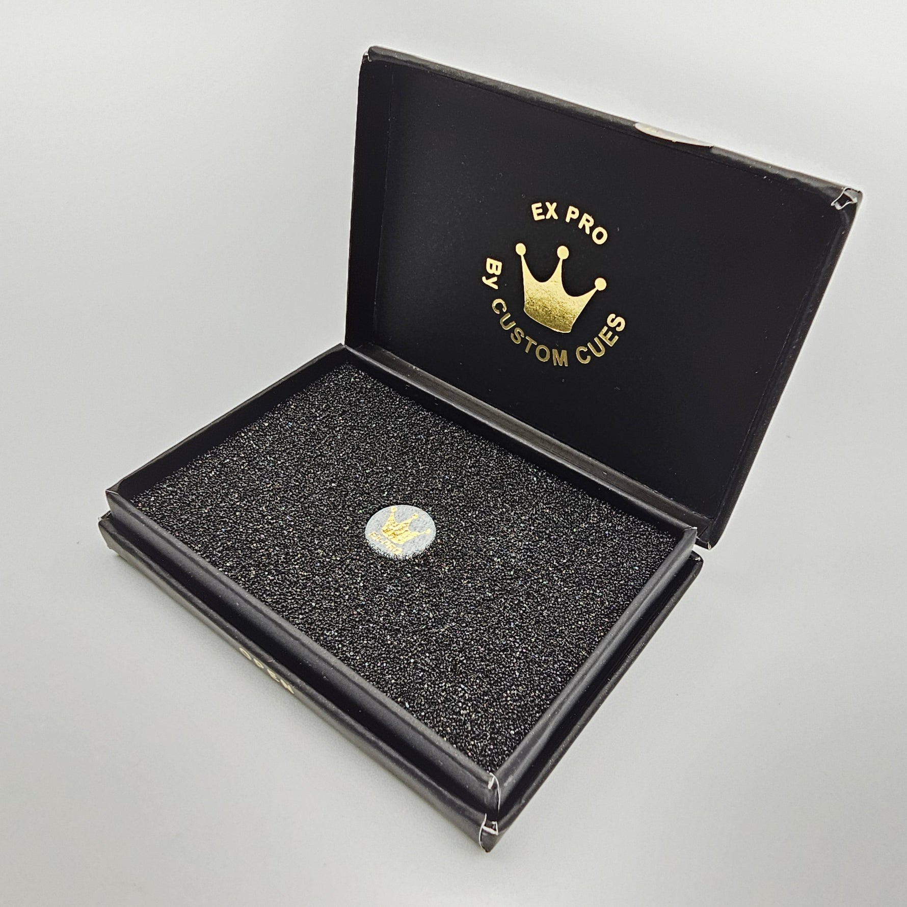 Open box of Triple Crown EXCEED-PRO Black Pressed Tip showing a single cue tip nestled in foam, ideal for serious pool and snooker players.