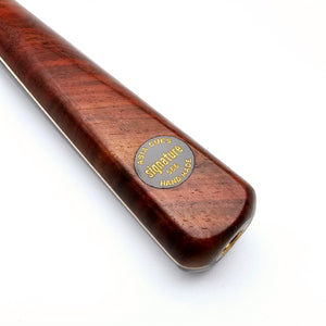 Close-up of Asia Cues Signature No.566 cue butt showing engraved gold badge on polished Siam rosewood, highlighting craftsmanship and branding.