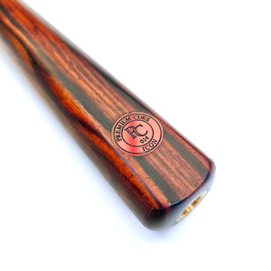 Close-up of Premium Cues ICON No.014 cue butt featuring red logo badge on cocobolo wood, highlighting craftsmanship and brand authenticity.
